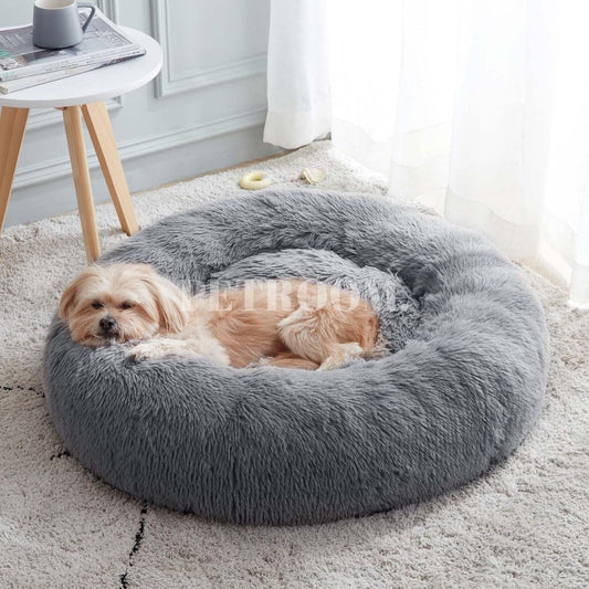 A grey dog bed on a carpet floor with a beige dog sleeping